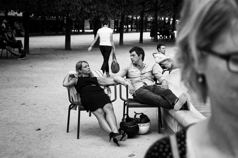 Three people seated at an outdoor café, black and white