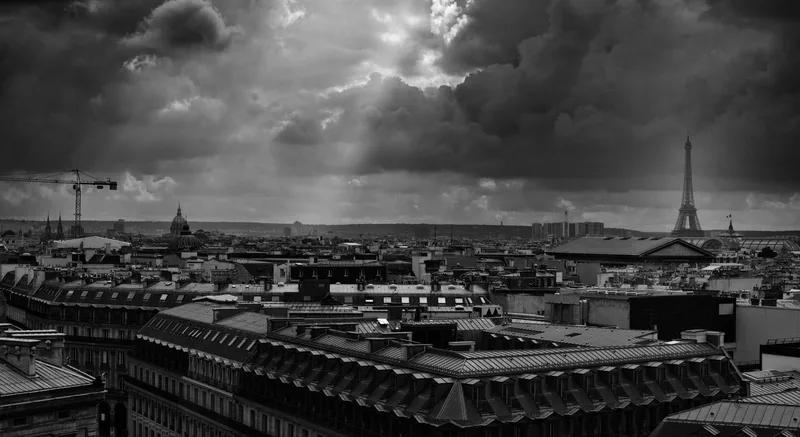 Rooftops toward the Eiffel Tower under storm cloud, black and white
