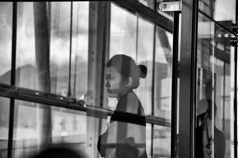 Woman behind a window frame, reflections, black and white