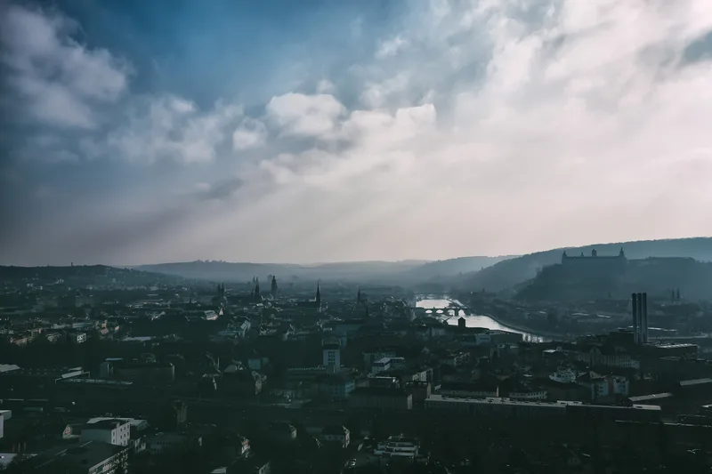 Wooded hills above a river valley under broken cloud