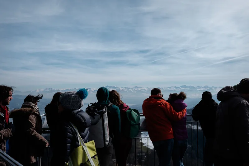 Crowd at a viewpoint railing under a pale wide sky