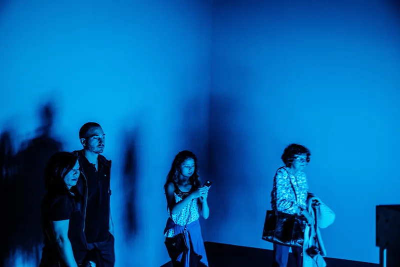 Three people in a corridor washed in deep blue light