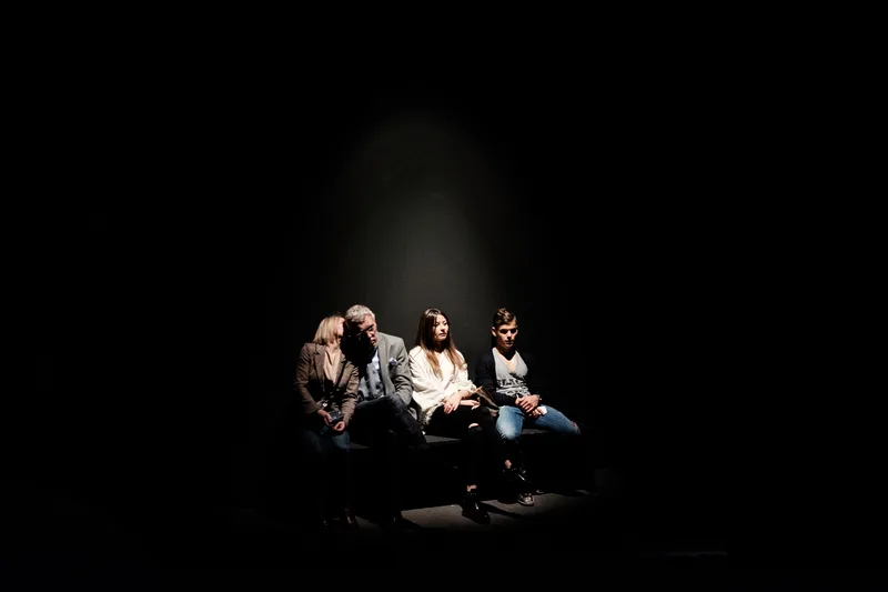 Small group seated in a pool of light in darkness