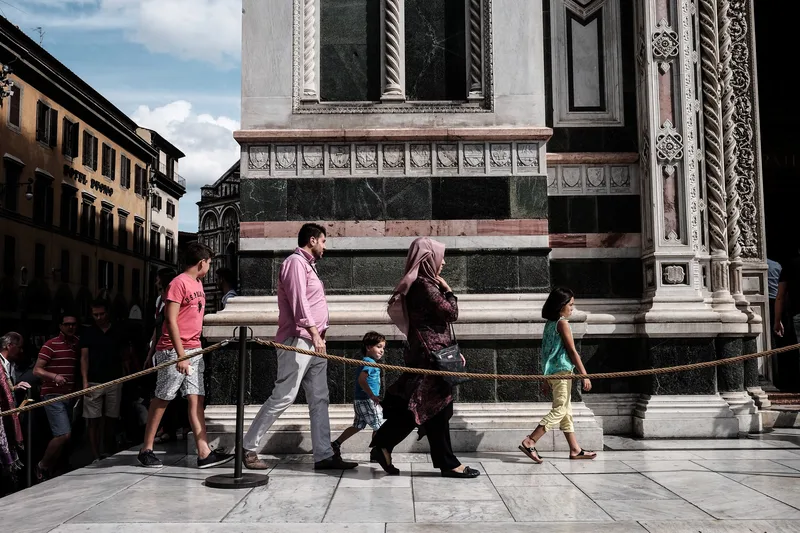 People walking past a striped marble cathedral wall