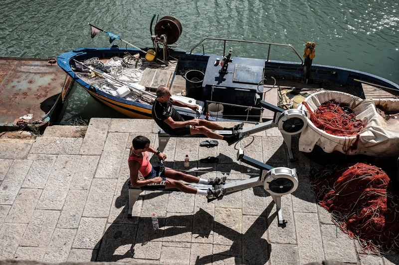 Fishing boat moored beside coiled red nets on a stone quay