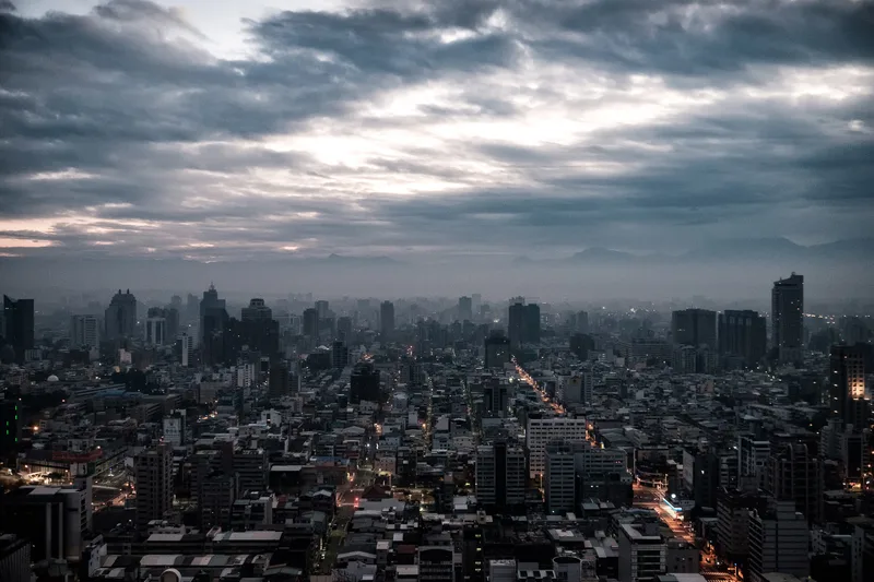 Dense city grid at dusk under a heavy cloud bank