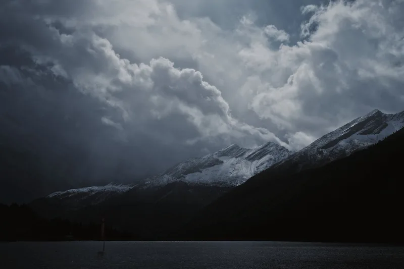 Snow-covered peaks beneath a towering bank of cloud