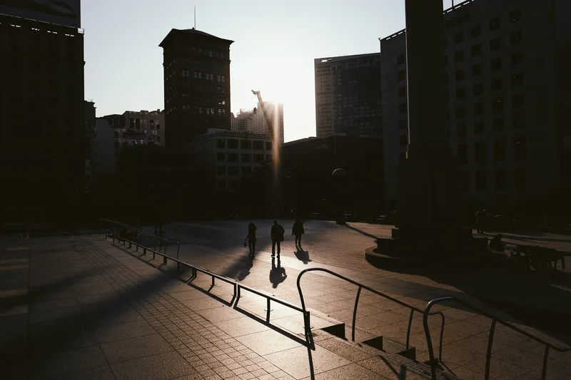 Empty plaza in low sun, long shadows across the paving