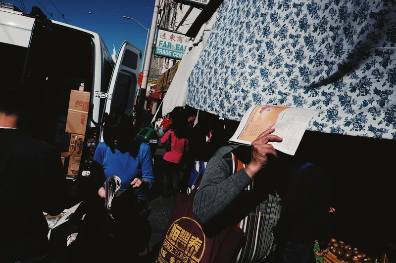 Market crowd beneath a blue and white patterned canopy