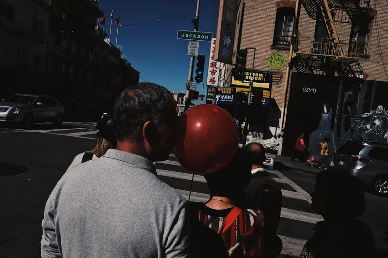 Crowd waiting at a crossing, a red balloon among them