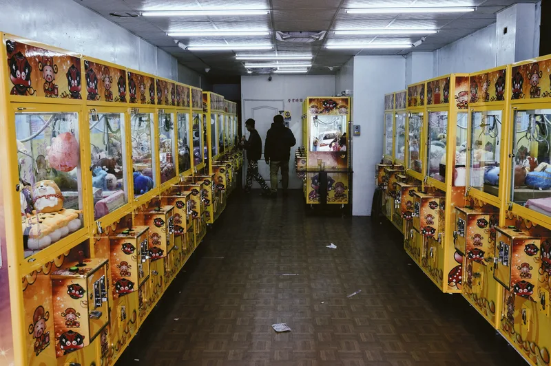 Narrow corridor lined with yellow claw-machine cabinets