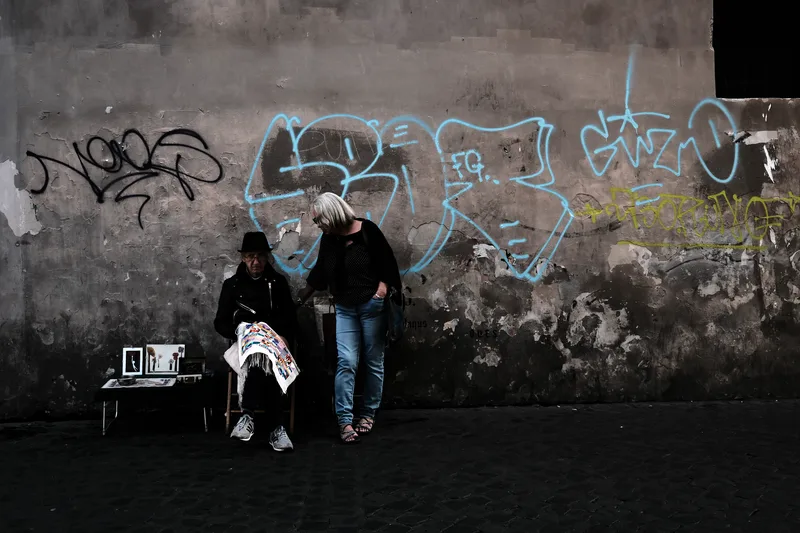 Two people sitting against a graffiti-covered wall