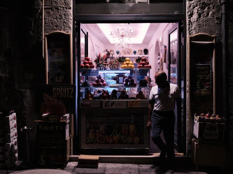 Brightly lit shop doorway in a dark stone street at night