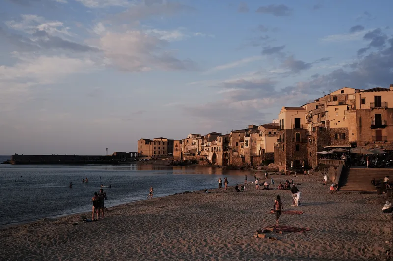 Old seafront town at dusk, people on the beach below