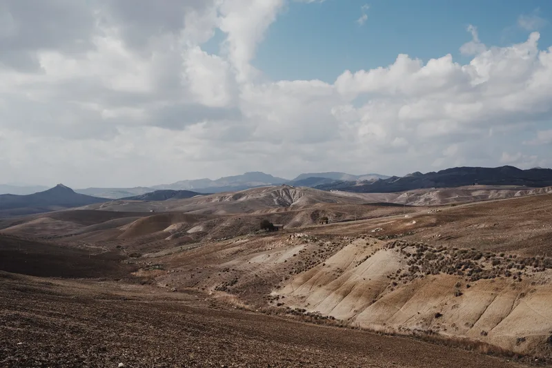 Barren ridged hills under a wide clouded sky
