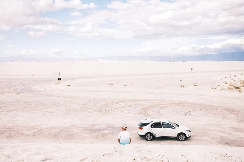 White car parked on a vast salt flat under wide sky
