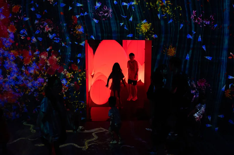 Children silhouetted against a glowing red installation