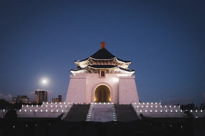 Floodlit ceremonial gateway at night below a full moon