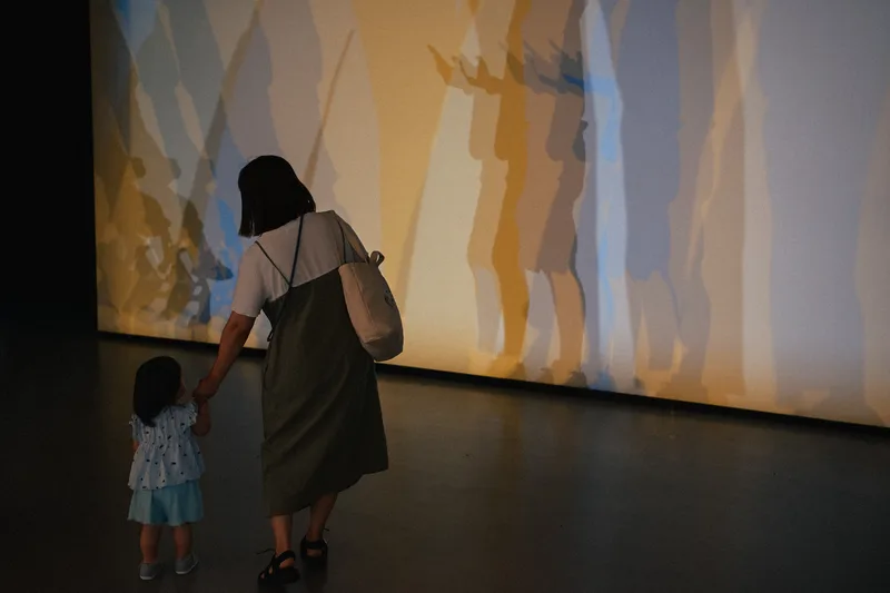 Woman and child before a large softly lit projection