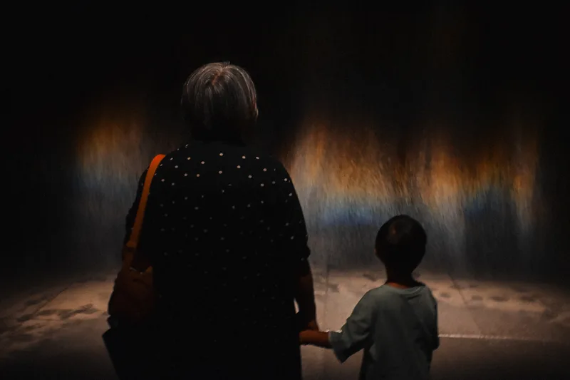 Woman and child before a dark projected artwork