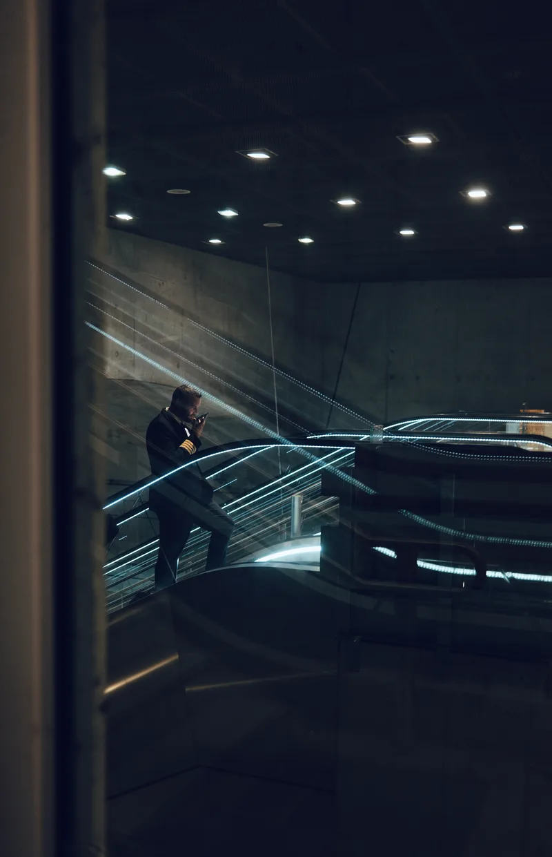 Figure on an escalator seen through a dark glass wall