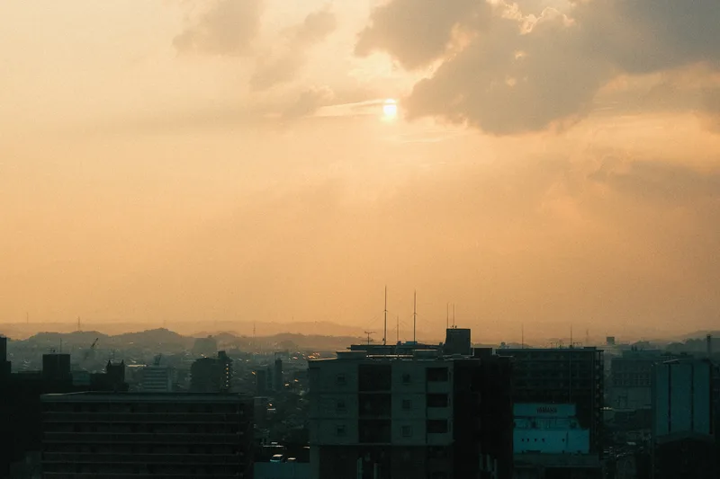 Sun low over a hazy city, warm sky above rooftops