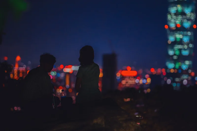 Blurred figures against out-of-focus neon city lights at night
