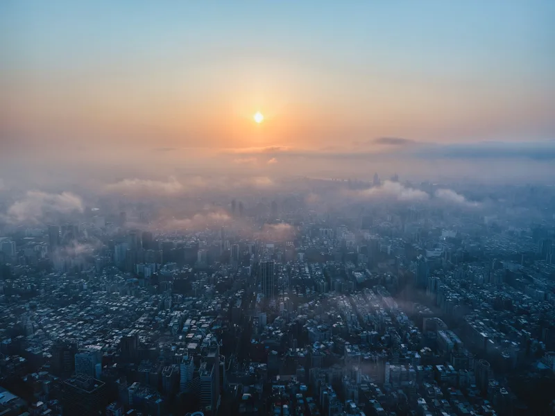 Sun rising over a city through low mist, from above